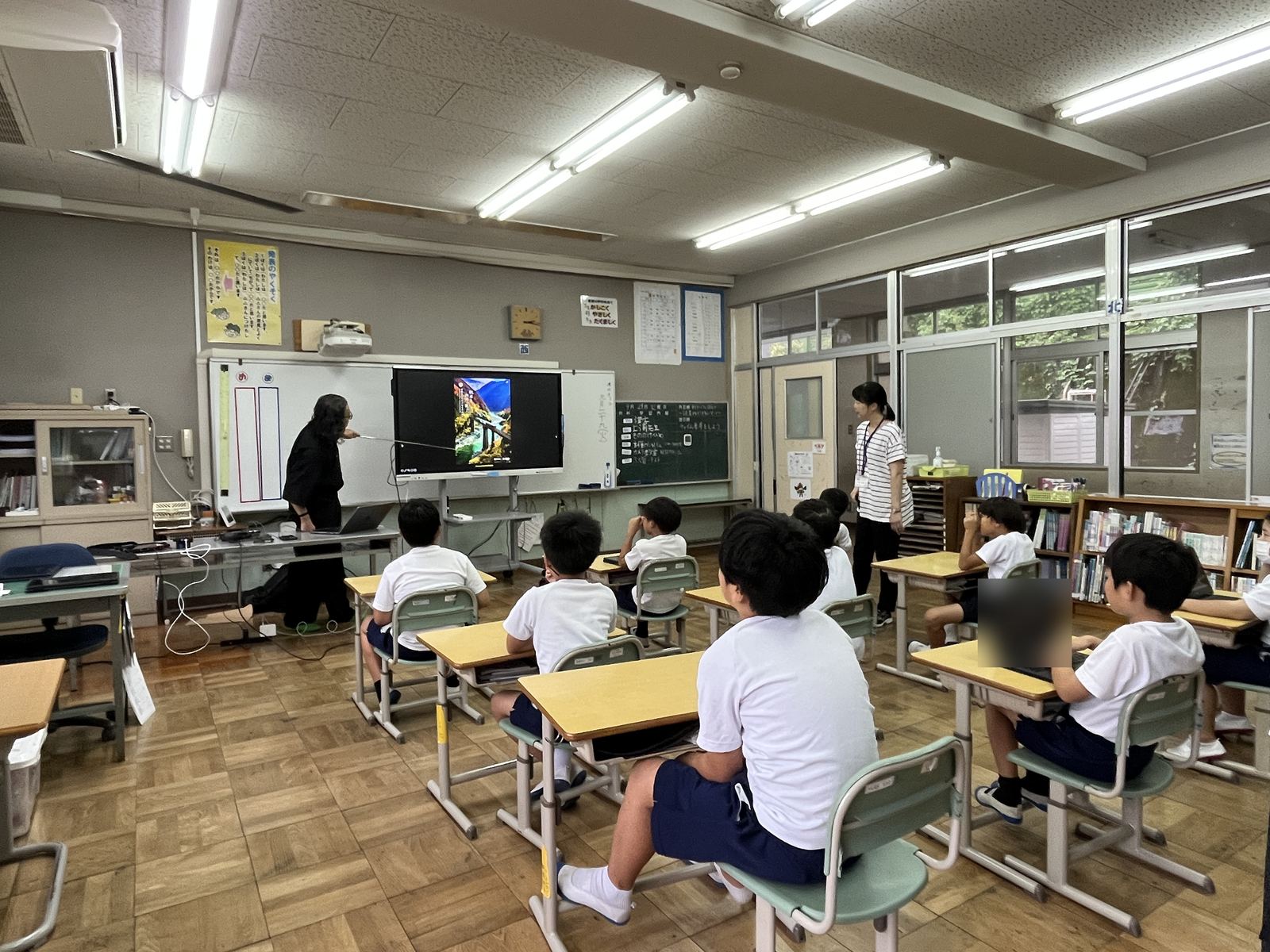 教室の後方から見た授業の様子。児童たちがモニターの写真に注目している