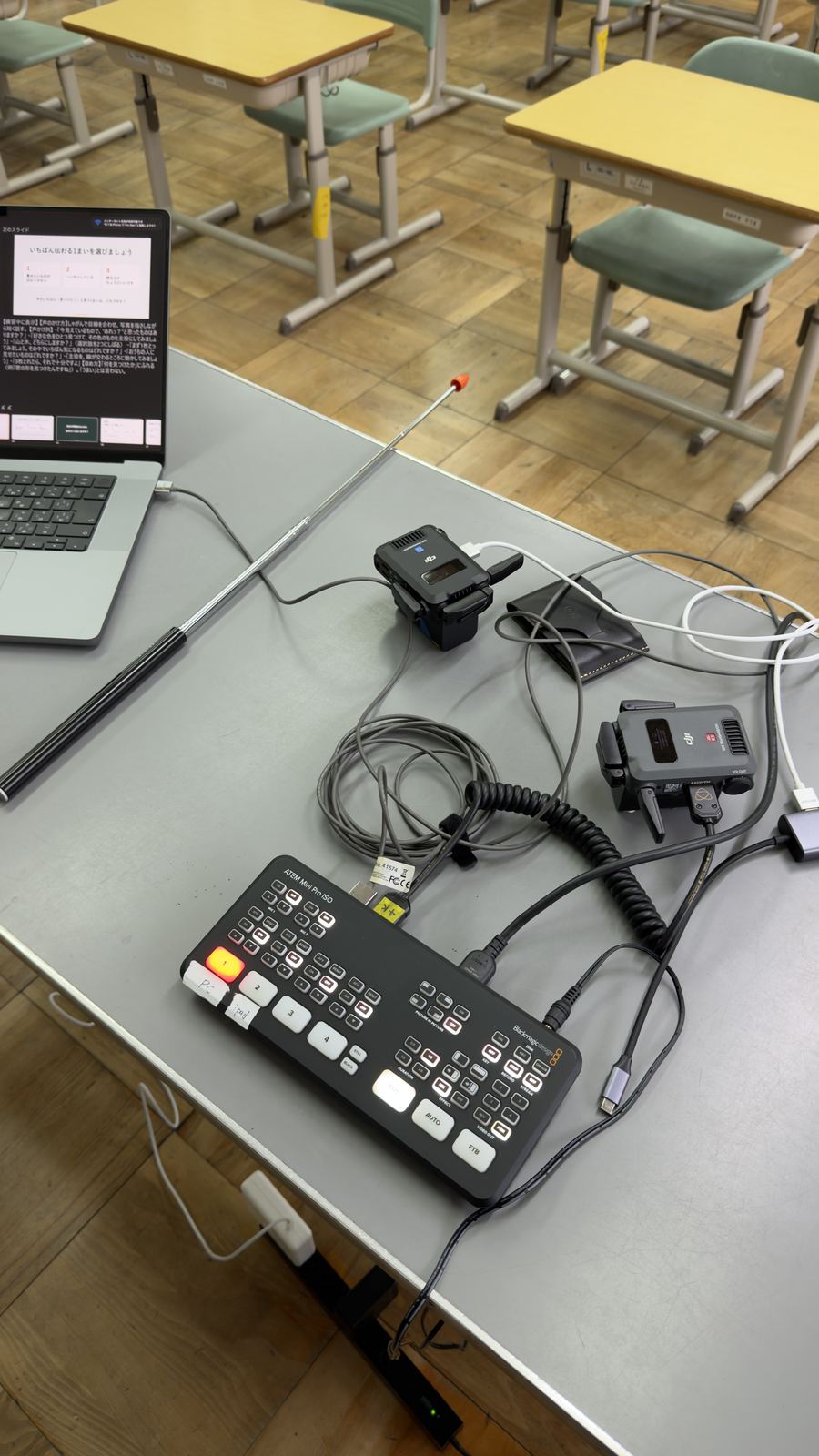 映像スイッチャーとワイヤレスマイクの受信機を机の上で接続している様子